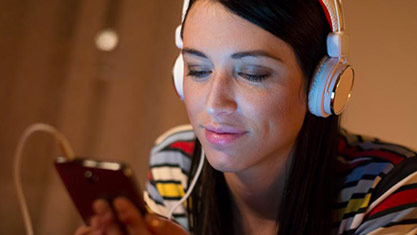 Woman wearing headphones, viewing her phone
